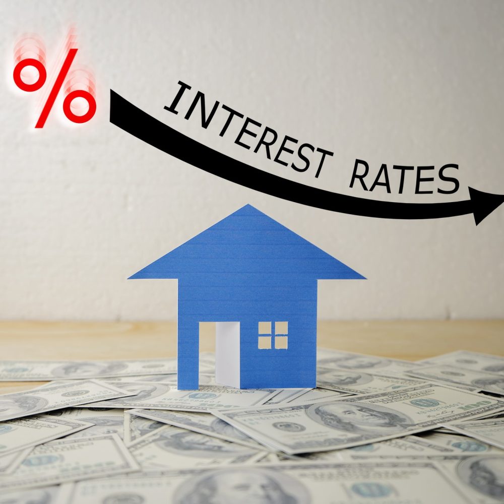 HOUSE STACKED US QUARTER DOLLAR ON WOODEN TABLE WITH BLACK ILLUSTRATION SHOWS DECREASING OF INTEREST RATES / FINANCIAL CONCEPT